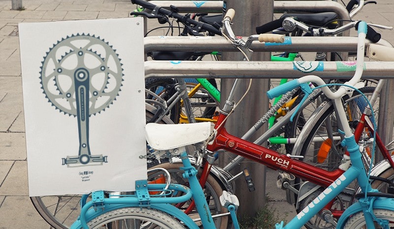Pédale | Gay Dictionary, France Photograph of a few parked bicycles, in the first of them there is a poster with the illustration Pédale.