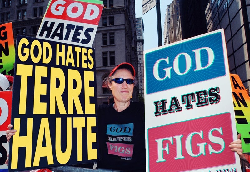 Fotografía de la dueña de la Secta Baptista de Westboro con un cartel donde pone, God Hates Figs, Dios odia a los higos.