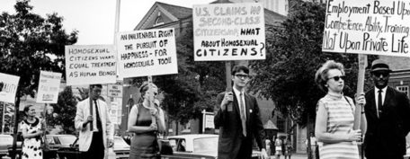 Fotografía en blanco y negro de una manifestación de La Mattachine Society, vestidos según los cánones imperantes reivindicando los derechos de las personas homosexuales.