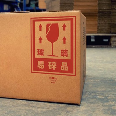 Fotografía en color de una caja con la clásica advertencia "contiene cristal" que es el diseño bōlí.