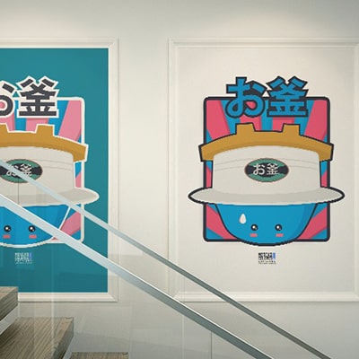 Fotografía en color de los dos diseños Okama impresos en póster y colgados de una pared