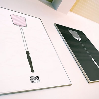 Fotografía de 2 pósteres con el diseño Tapette, uno en color y otro en blanco y negro, colgados de una pared.