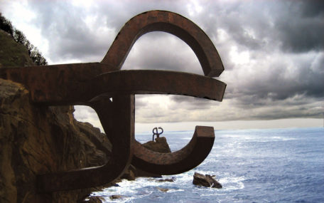 Fotografía de una parte de "el peine del viento" con nubarrones al fondo y el mar debajo.