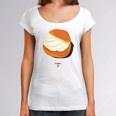 Fotografía en primer plano de una camiseta blanca que lleva una chica con el diseño Bollo, un bollo relleno de crema en colores blanco, marrón y naranja.