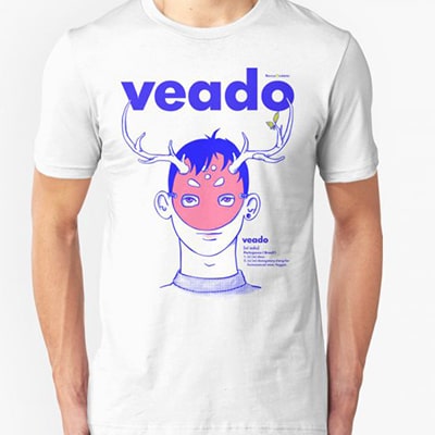 Fotografía en primer plano de una camiseta blanca que lleva un chico con el diseño Veado, el busto de un chico con una máscara con cuernos de venado, con la palabra veado en la parte superior, en colores azul y rosa.
