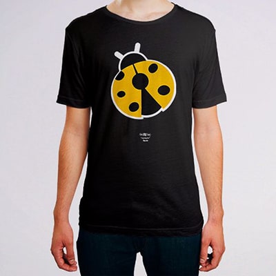 Close-up photograph of a black t-shirt worn by a boy with the Mariquita drawing, the insect in black, white and yellow colors