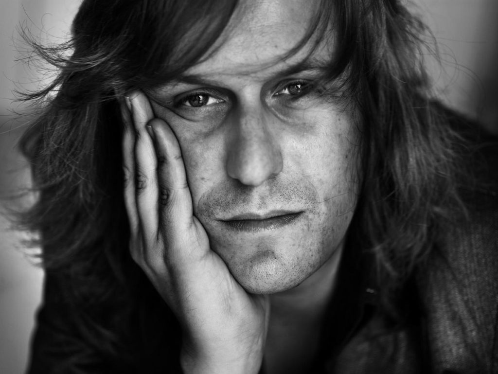Nacho Vegas. Fotografía de primer plano, apoyando la cara en la mano, en blanco y negro.